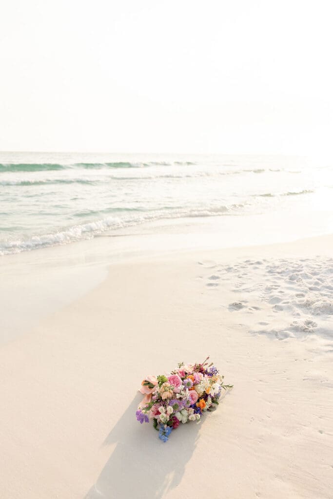 Floral bouquet from wedding sitting on the sand of a Florida beach | Madison Abernathy Photography
